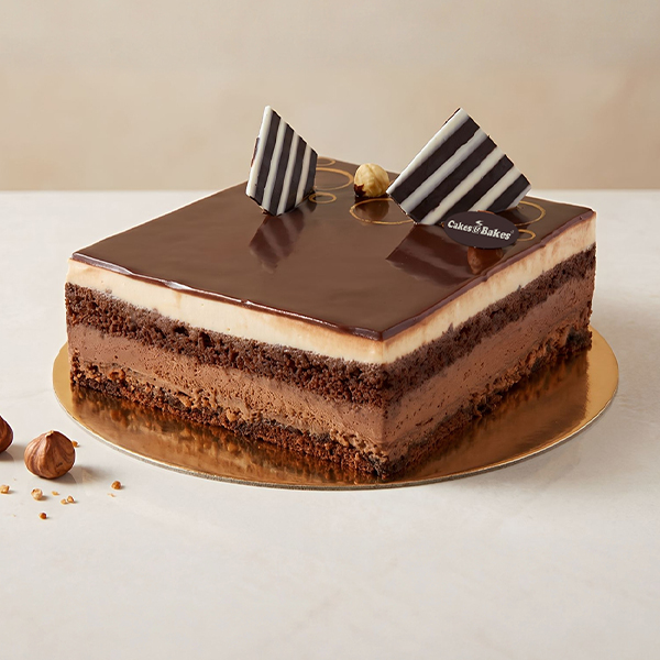 Chocolate Noisette Cake from Cakes and Bakes Bakery Dubai with glossy chocolate glaze, hazelnuts, piped chocolate decorations and crunchy praline shards.