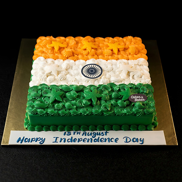 Indian Independence Day Tricolor Cake with saffron, white and green buttercream rosettes, edible Ashoka Chakra, Happy Independence Day plaque, and star decorations by Cakes and Bakes Bakery Dubai.